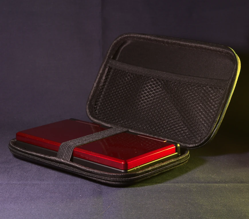 Anbernic RG DS in Black and Crimson Red sitting inside its official carrying case, shown at a 45-degree angle — the dual-screen handheld fits snugly with room for accessories`